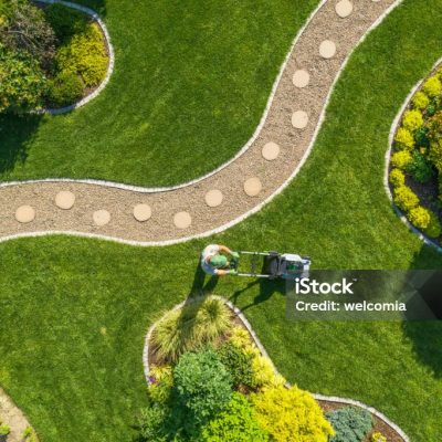 Aerial View of Big Garden Grass Field Mowing by Caucasian Gardener. Summer Time Landscape Maintenance.